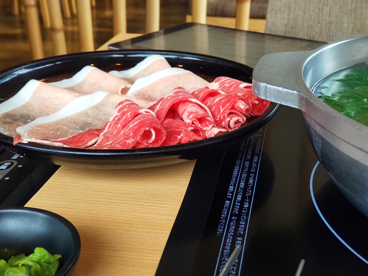 A table set for shabu-shabu with thinly sliced meat