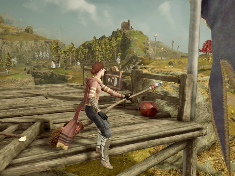 The player character, wearing a Quidditch uniform, is riding a broom at the ruins of the Quidditch pitch