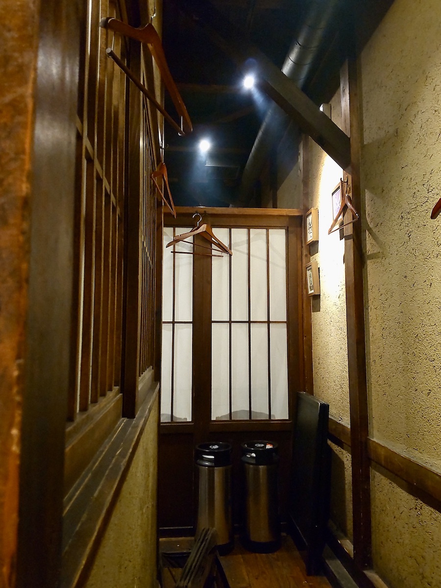 A quiet hallway of a Japanese restaurant featuring soft lighting and natural wooden textures