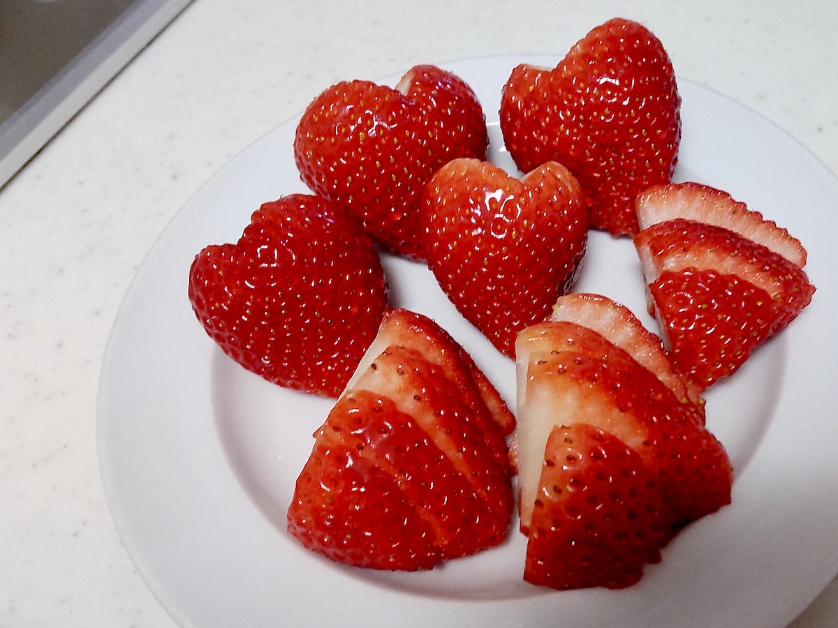 Sliced strawberries on a plate, including heart-shaped pieces