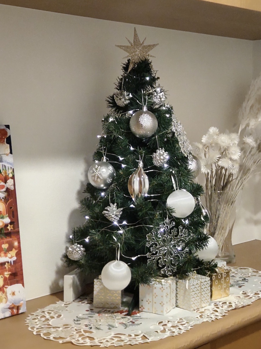 A Christmas tree decorated with white and silver ornaments