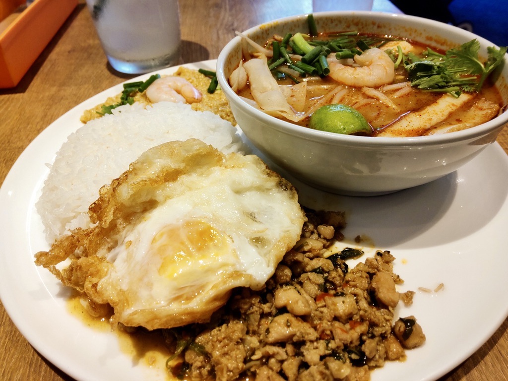 A single plate with gapao rice, egg curry stir-fry, and tom yum goong. （
