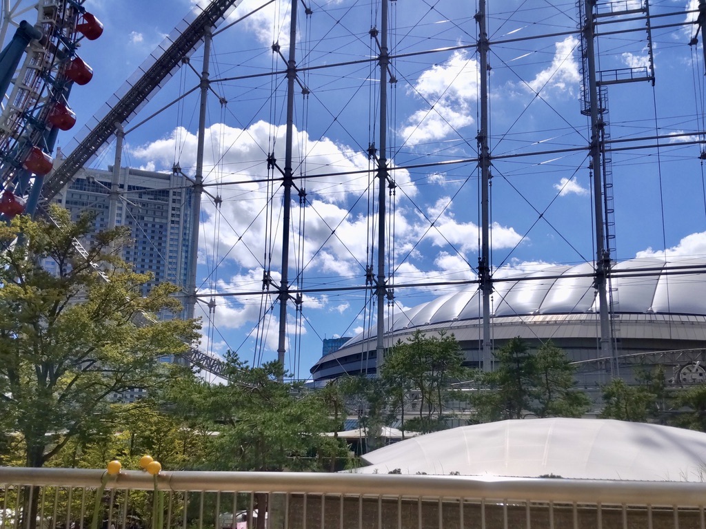 The white Tokyo Dome behind the Ferris wheel and the roller coaster.